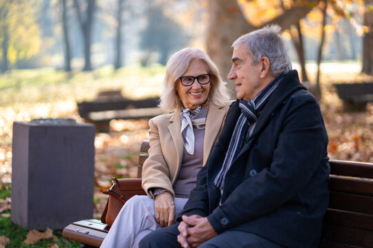 Happy senior couple enjoying a conversation while sitting on a park bench - Powered by Adobe