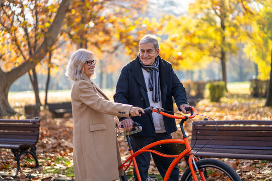 Happy senior couple enjoying a bike ride together in a beautiful autumn park