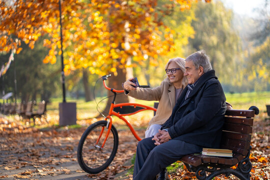 Happy senior couple taking a selfie in a park on a sunny autumn day