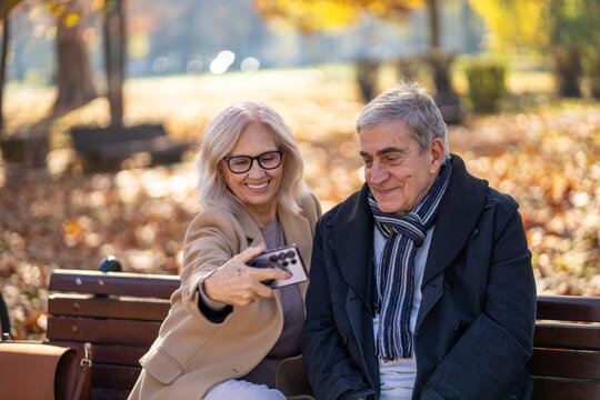 Happy senior couple taking a selfie together in a beautiful autumn park