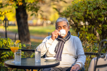 Senior man enjoying coffee outdoors on a sunny autumn day
