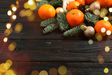 Fresh tangerines, Christmas ornaments and fir tree branches on wooden table, bokeh lights
