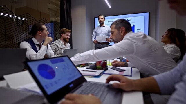 A diverse team of business professionals gathers in a modern office, actively engaging in a presentation. They collaborate on ideas, discuss financial data, and analyze strategies for company success. - Powered by Adobe