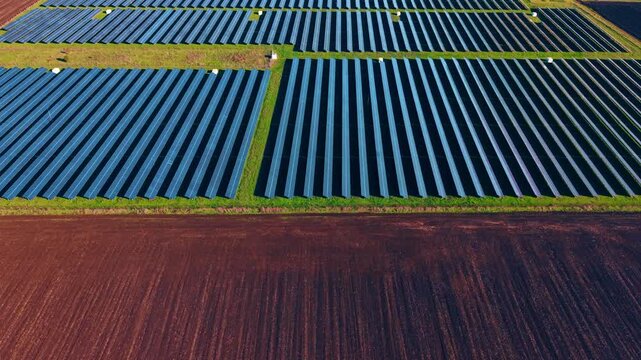 Flying over the dug plantation to approach the solar panel field. Production of green energy form solar power.