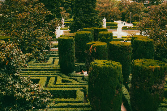 Formal garden with trimmed hedges and statues. A beautiful formal garden features meticulously trimmed hedges, pathways, and elegant statues, creating a serene and picturesque landscape.