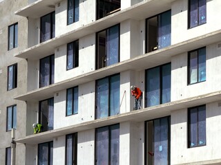 construction worker scraping and cleaning balcony floor of building under construction