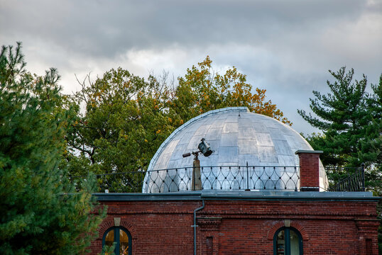 View of the gleaming silver dome of an observatory rises above a red brick building, framed by the green and autumnal trees, Vassar College Campus, Poughkeepsie, New York, United States.