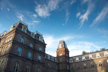 View of an old brick building standing proudly against a vibrant blue sky dotted with wispy clouds, a timeless scene, Vassar College Campus, Poughkeepsie, New York, United States.