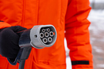 fast charging connector Close-up, electric car charging plug held man in orange jacket, connection...