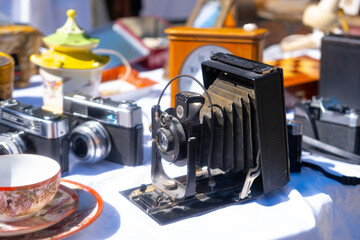 vintage folding bellows film camera, retro design, antique teacup, clock on table European flea market, nostalgia and collecting, Nostalgia and photography history, hobbies concept, used things