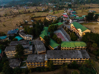Aerial view of buildings with green roofs nestle amidst the landscape, forming a tapestry of textures and tones, Baijnath, Himachal Pradesh, India.