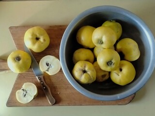 quince whole and cut in half with a knife on a wooden board and in a bowl
