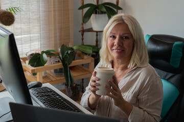 Woman working from home holding coffee cup smiling