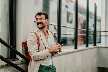 Man smiling, using phone, waiting at train station