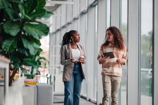 Coworkers walking and talking in modern office - Powered by Adobe