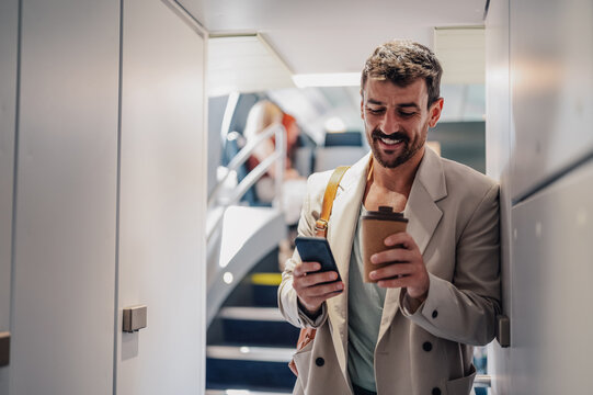 Smiling traveler looking at smartphone while holding coffee