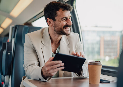 Smiling man commuting by train using tablet