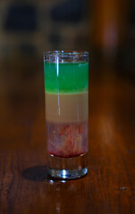 Close-up of bartender preparing colorful layered cocktail with ice using tongs. Glass, shaker, and vibrant drink setup evoke nightlife and mixology atmosphere. High quality photo