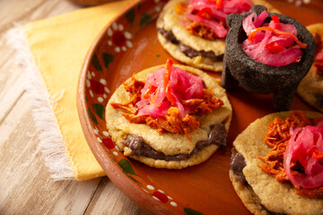 Panuchos, a typical dish from Yucatan, Mexico. A handmade, fried corn tortilla filled with beans, topped with cochinita pibil, pickled red onion, and habanero pepper.