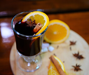 An overhead view of a glass of mulled wine, garnished with a clove-studded orange slice. The scene...
