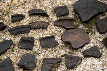 Fragments of ancient black pottery on a granite stone The Puzzle of the Past