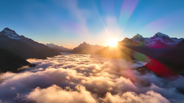 The sun rises majestically over the rugged mountains, illuminating the thick blanket of clouds that covers the valley below. The golden light reflects off the peaks, creating a bre