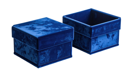 Close-up of two elegantly crafted, royal blue velvet boxes, one closed, one open, both set against a deep black background