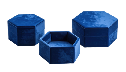 Three hexagonal, velvet-covered containers in shades of dark blue are placed against a black background. One is open, revealing an empty interior