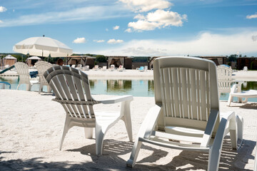 White deck chairs at a recreation center with a freshwater lake