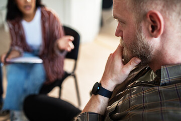Adult man listening thoughtfully during support group in meeting room