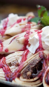 Close-up on a delicious pancake with chocolate. rolls with cottage cheese, poppy seeds, cream and cherry sauce, decorated with mint.