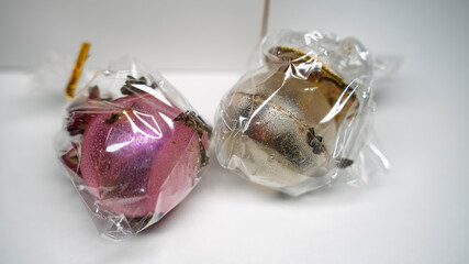 Artisan blooming tea bombs, individually wrapped with dried fruits and flowers, presented in a...