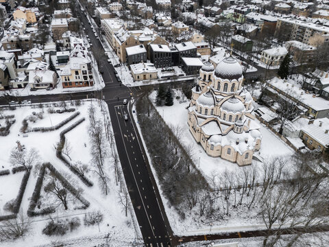 Aerial view of a snow-dusted cityscape featuring the prominent St. Michael and St. Constantine Church, its domes gleaming softly against the winter sky, Vilnius, Vilnius, Lithuania.