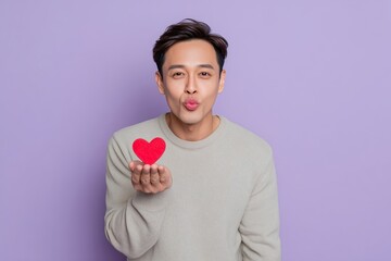 Man Blowing a Kiss While Holding Red Heart on Purple Background