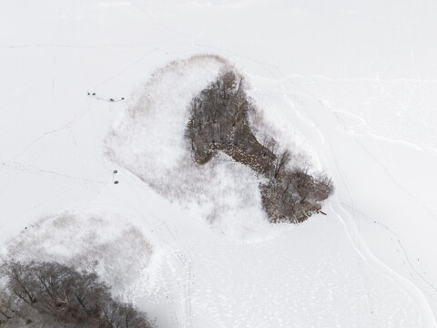 Aerial view of islands emerging from a frozen expanse, their silhouettes stark against the white canvas of ice and snow, Trakai, Trakai, Lithuania.