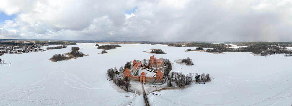 Fototapeta Aerial view of Trakai Island Castle standing boldly against the stark white canvas of the frozen lake, its red brick contrasting with the winter landscape, Trakai, Trakai, Lithuania.