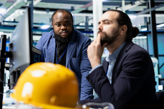 Multiethnic solar panel engineering team shares data insights in factory, working on clean renewable energy manufacturing. Supporting sustainable power with innovation and teamwork.