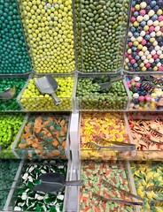 A colorful assortment of gummy candies displayed in transparent bins inside a candy shop. 
