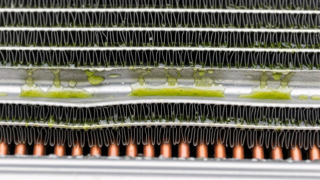 Close-up of a vehicle radiator with fluid leak showing corrosion and maintenance issues, ideal for automotive repair and service themes