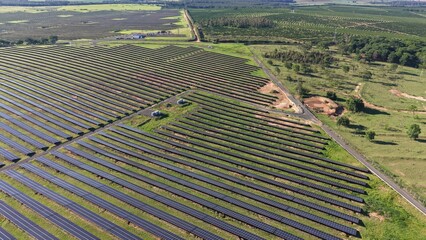 Aerial view of extensive solar panel array in a field with trees and vegetation surrounding it © Felippe Lopes