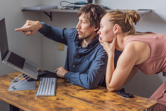 A man and his wife working from home together in their shared home office, focused on laptops in a bright modern workspace. Remote work, teamwork, productivity and contemporary work-life balance