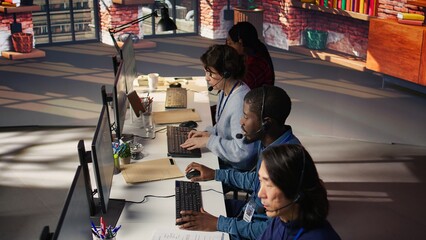 Team of multiethnic call center agents in workplace helping customers. Multiracial workers in diverse customer center assisting clients needing help resetting password, camera B
