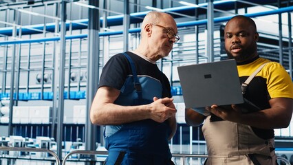 Smart factory senior engineer teaches intern to implement automated workflows, computerizing manual operations. Experienced man helping trainee integrate sensors into production, camera A