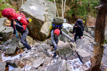 Active adventure: three young backpackers making their way up a steep boulder strewn trail in Killarney Park Ontario © Michael Connor Photo
