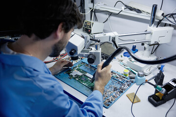 Man is repairing on electronic repair workbench equipped with circuit board