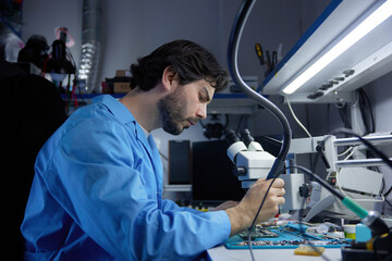 A skilled technician diligently repairing laptop while working under a microscope