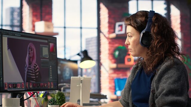 Female graphic designer editing photos on a modern computer setup in agency office, using an enhancement technique. Ideal workspace for a digital design professional, photography. Camera B.