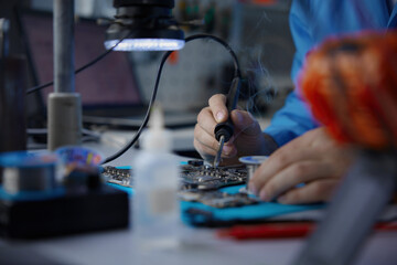 Electronics repair skilled technician engaged in detailed motherboard work for repairs and fixes