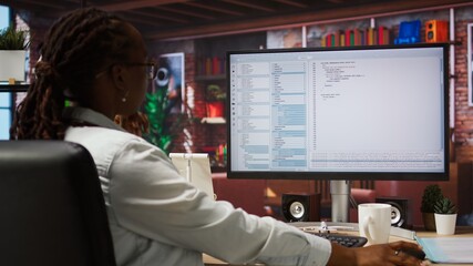 System administrator types code into PC, developing software, entering commands. IT professional at home fixing errors in application, implementing new features, listening music, camera A jib up shot