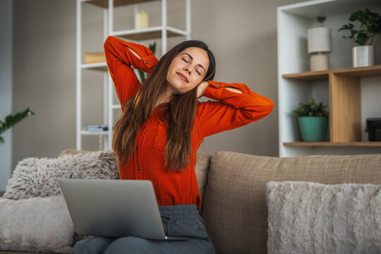 Woman stretching while working from home on a laptop
